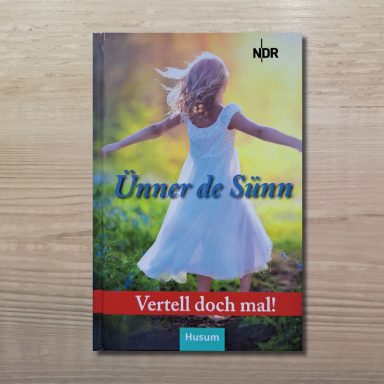 Buchcover mit einem Mädchen im weißen Kleid, das mit ausgebreiteten Armen auf einer Wiese läuft, Titel 'Ünner de Sünn', NDR-Logo oben rechts